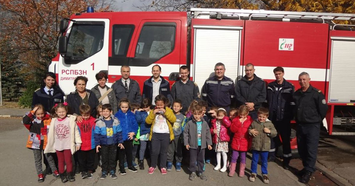 Students and fathers stand in front of a fire truck.